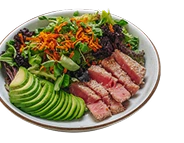 Ensalada fresca con láminas de atún sellado, palta en rodajas, mix de hojas verdes y zanahoria rallada, servida en un plato blanco