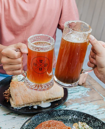 Brindis con cervezas artesanales en Sanguchería DoceTrece en Chile, sándwiches en mesa y experiencia para compartir con amigos