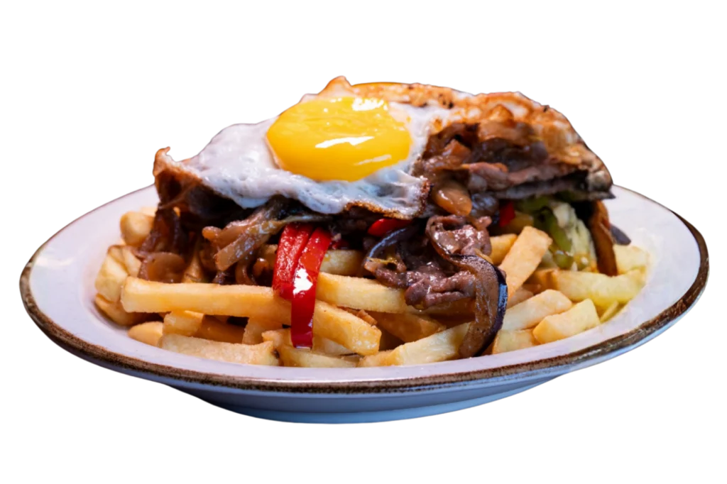 Chorrillana chilena de Sanguchería DoceTrece con papas fritas, carne salteada, cebolla y huevo frito, servida en plato