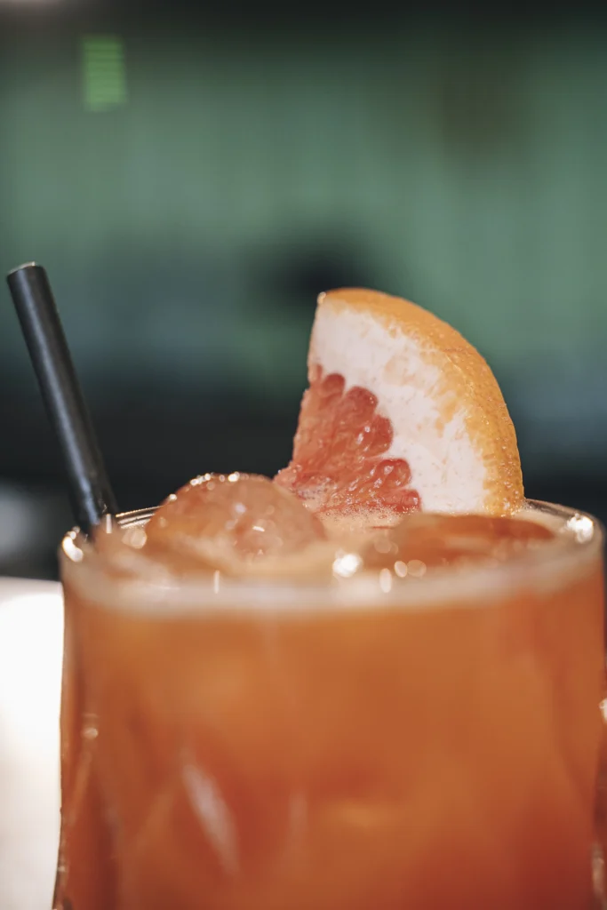 Cóctel de autor en Sanguchería DoceTrece en Chile con hielo y rodaja de pomelo, bebida fresca en primer plano