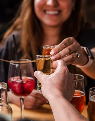 Brindis con shots y cócteles en Sanguchería DoceTrece en Chile, ambiente nocturno y mesa con bebidas para compartir