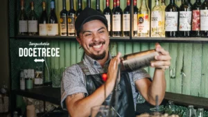 Bartender preparando destilados cóctel en la barra de Sanguchería DoceTrece en Chile, coctelería de autor con destilados y botellas en exhibición