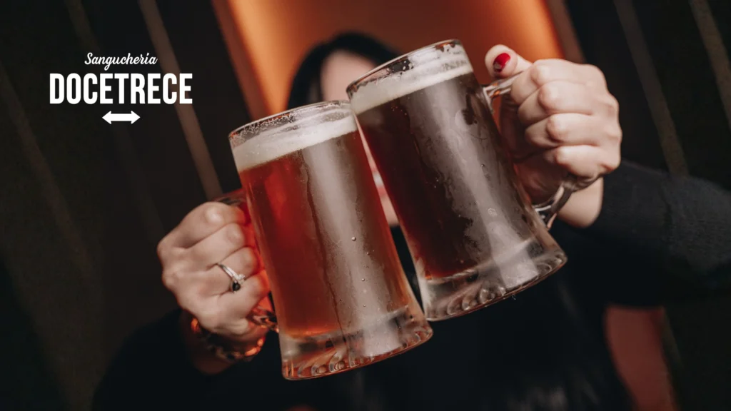 Brindis con cervezas artesanales en Sanguchería DoceTrece en Chile, dos schop fríos chocando en ambiente de bar nocturno. Levadora de la cerveza