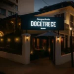 Fachada iluminada de Sanguchería DoceTrece en Chile de noche, entrada al restaurante y letrero Docetrece visible para reservas